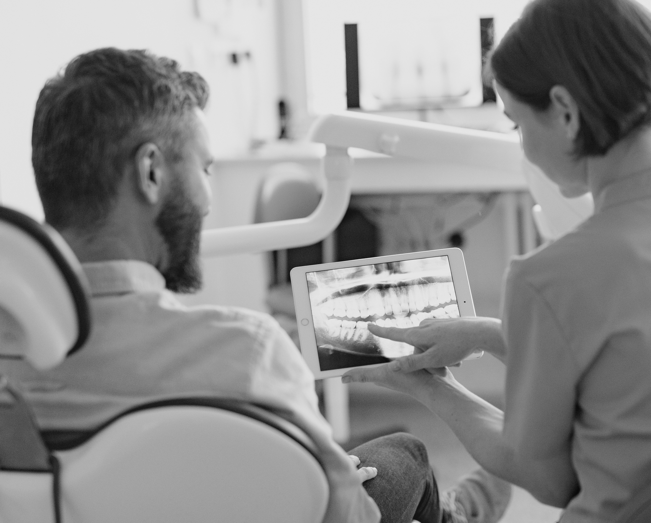 Zahnärztin zeigt einem Patienten ein Röntgenbild Zahnärztin zeigt einem Patienten ein Röntgenbild